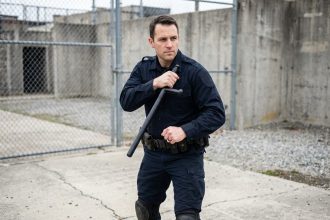 Policier en tenue tactique tenant un tonfa en position défensive lors d'un entraînement en extérieur