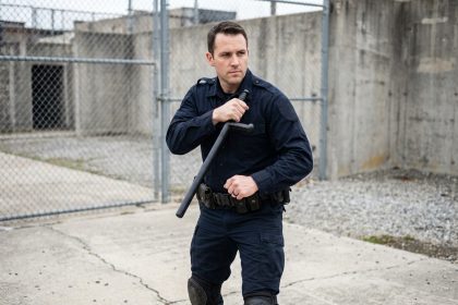 Policier en tenue tactique tenant un tonfa en position défensive lors d'un entraînement en extérieur